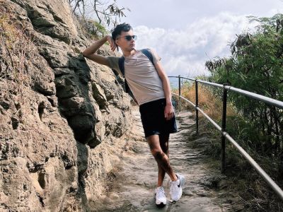 Sauriyan Sapkota is posing next to a rock using his hand to support his head.